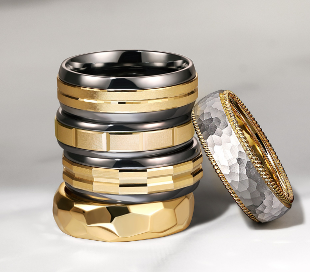 4 Silver and Gold Gabriel & Co. Wedding Bands stacked on top of each other with a fifth ring learning against them